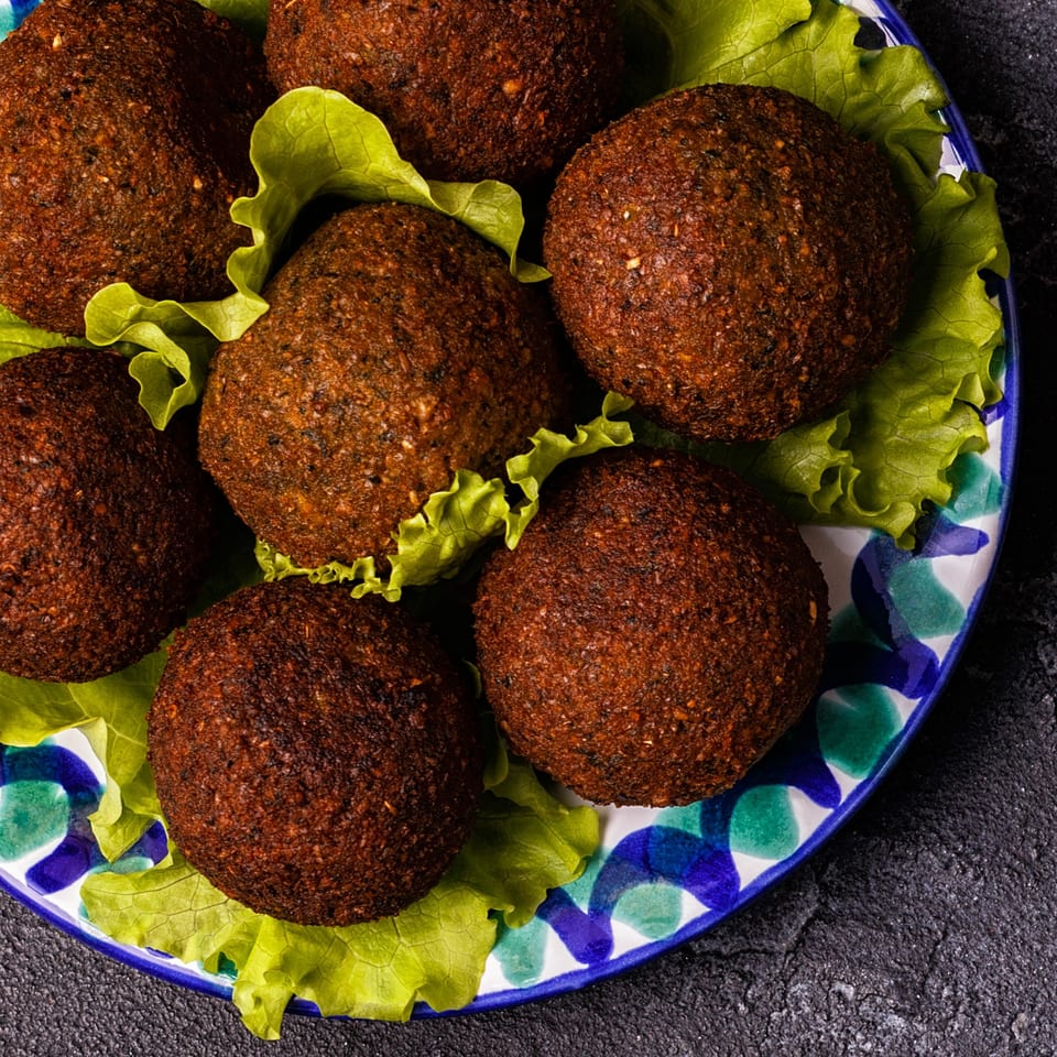 Crispy Mediterranean falafel balls on a bed of fresh lettuce, served on a decorative plate.