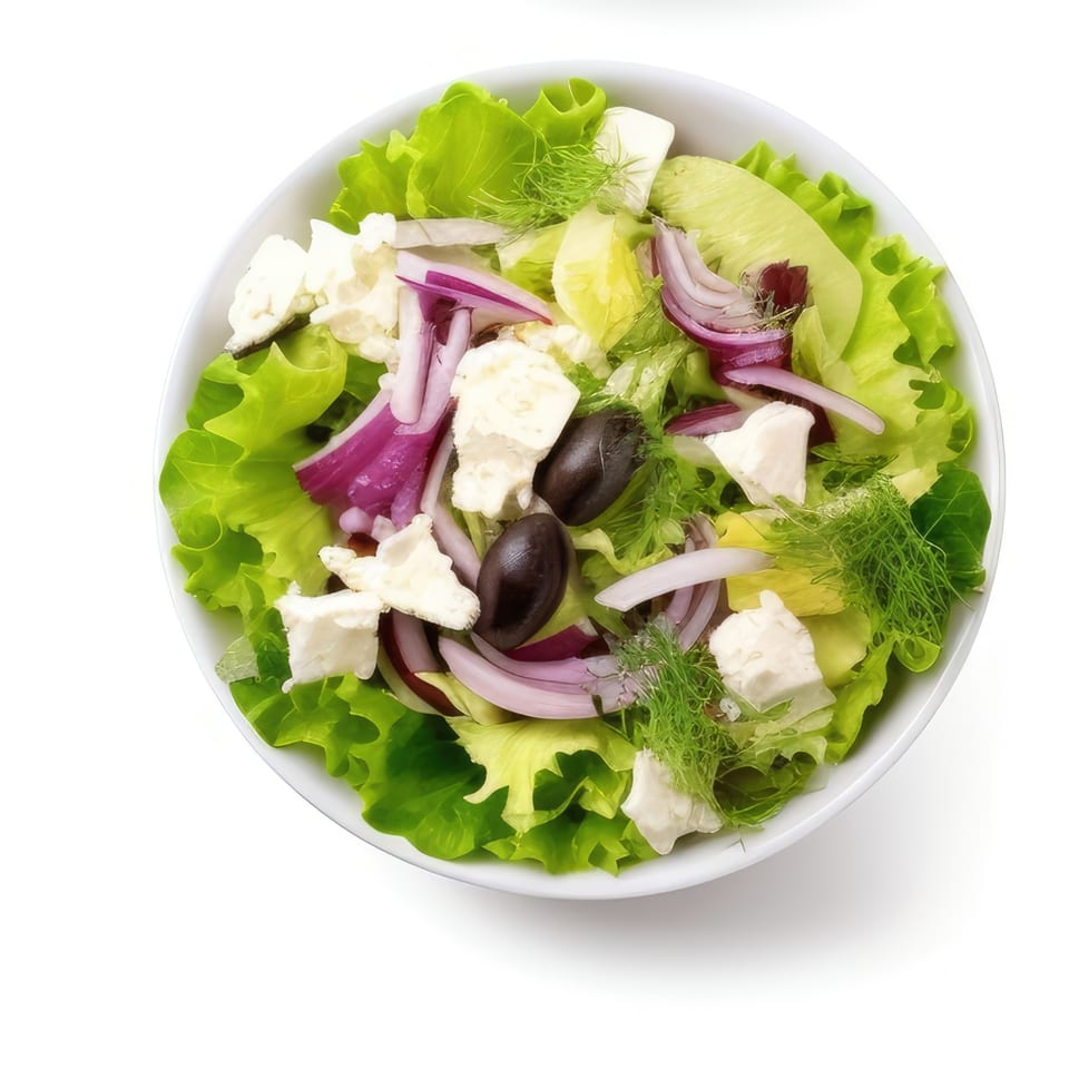 Overhead view of a Mediterranean salad with lettuce, red onion, feta, olives, and dill.
